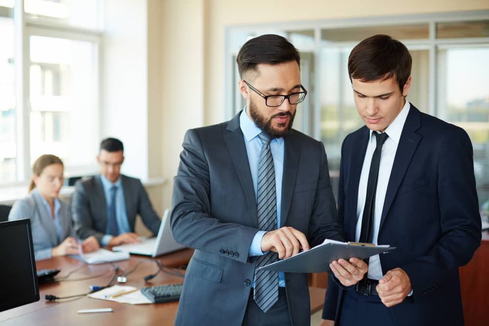 a group of men in suits looking at a clipboard